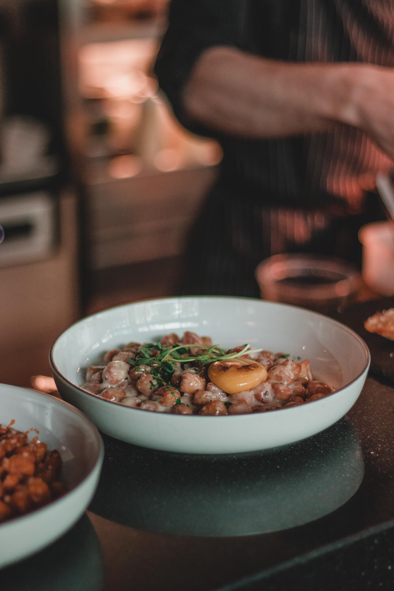 A chef in a professional kitchen skillfully preparing ingredients for a Korean Italian meal on a countertop.