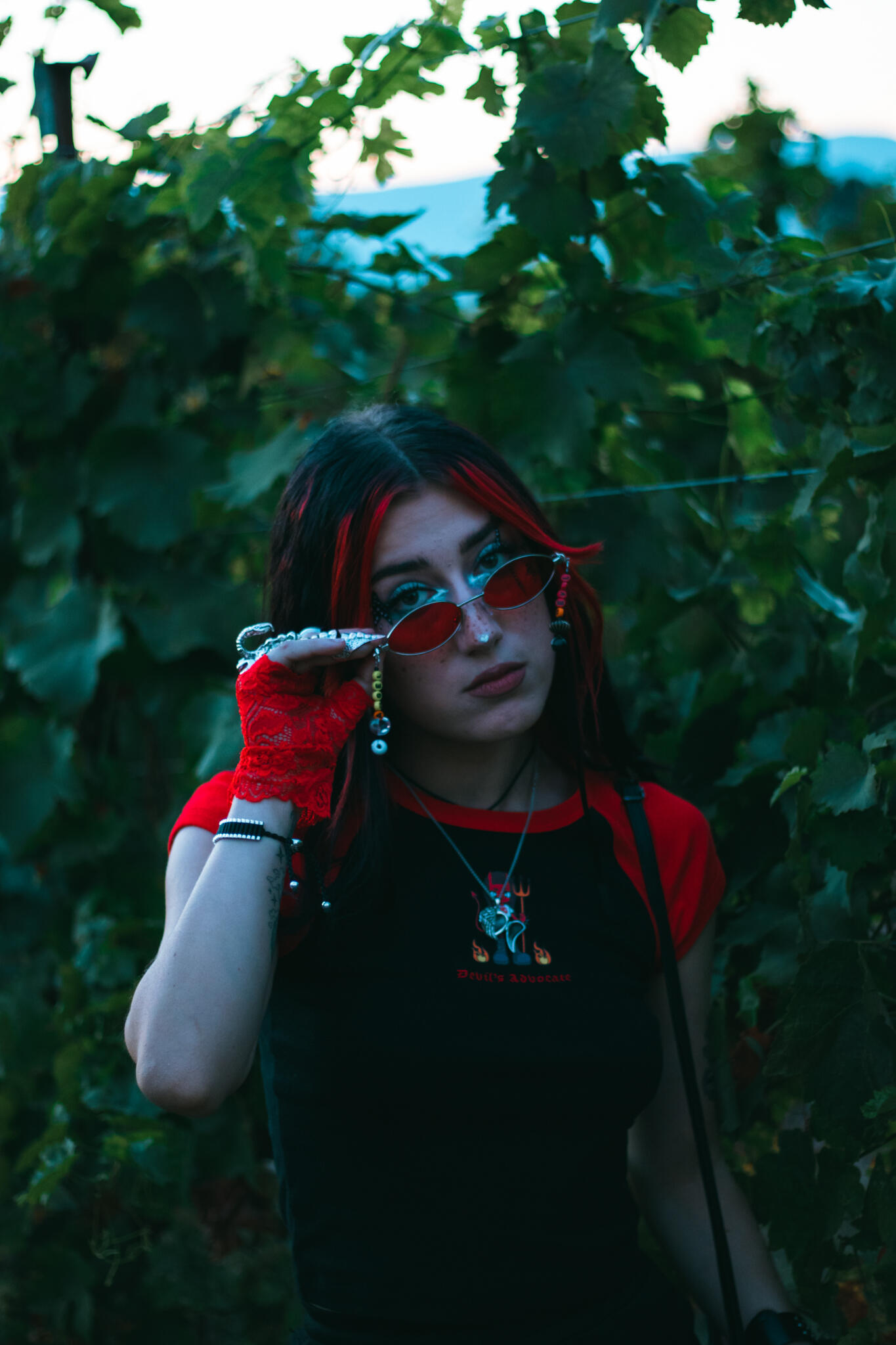 A woman with bright red hair and glasses looks directly at the viewer, emphasizing her distinctive hair color and eyewear style.