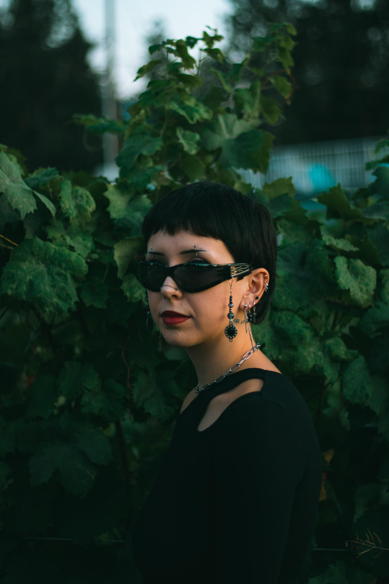A woman with sunglasses and a black top, showcasing a chic and modern look in a vineyard.