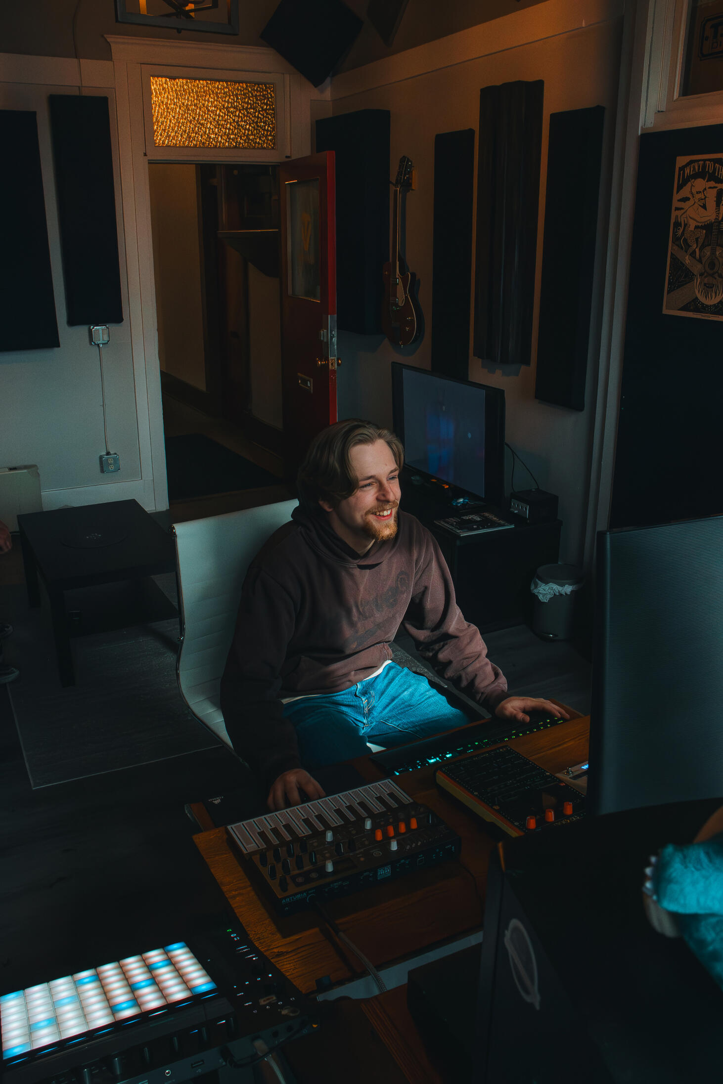Multiple high-quality MIDI pianos and devices used to produce, mix, and master different music tracks, featured on a clean wood shelf with light shining on them.
