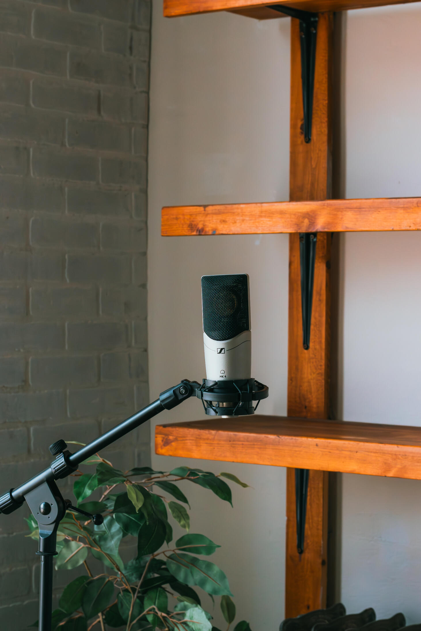 Multiple high-quality MIDI pianos and devices used to produce, mix, and master different music tracks, featured on a clean wood shelf with light shining on them.